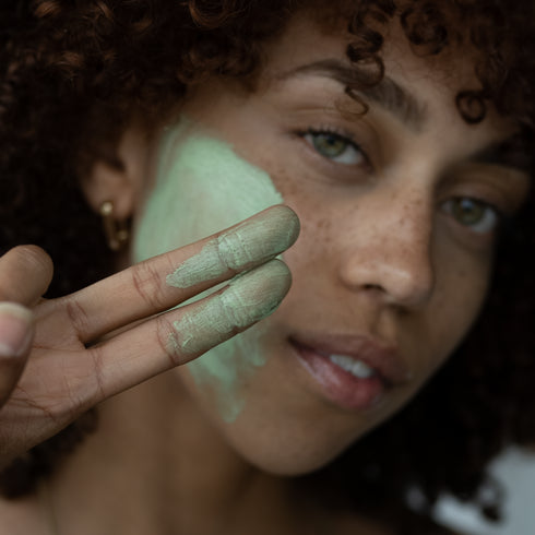Woman showing the Potent C Superfood Masque 50ML that's applied in her fingers and face